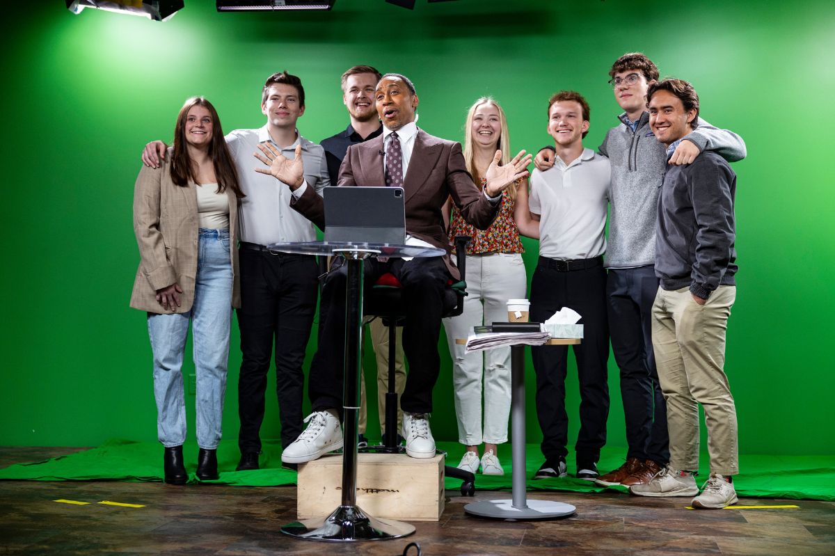 Student stand in front of a green screen.