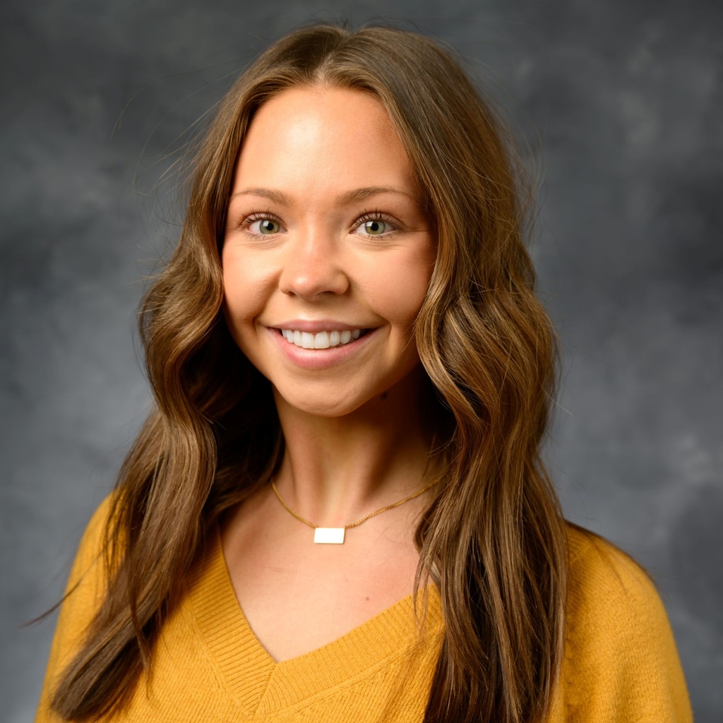 A portrait photo of Taylor Nelson on a gray background.
