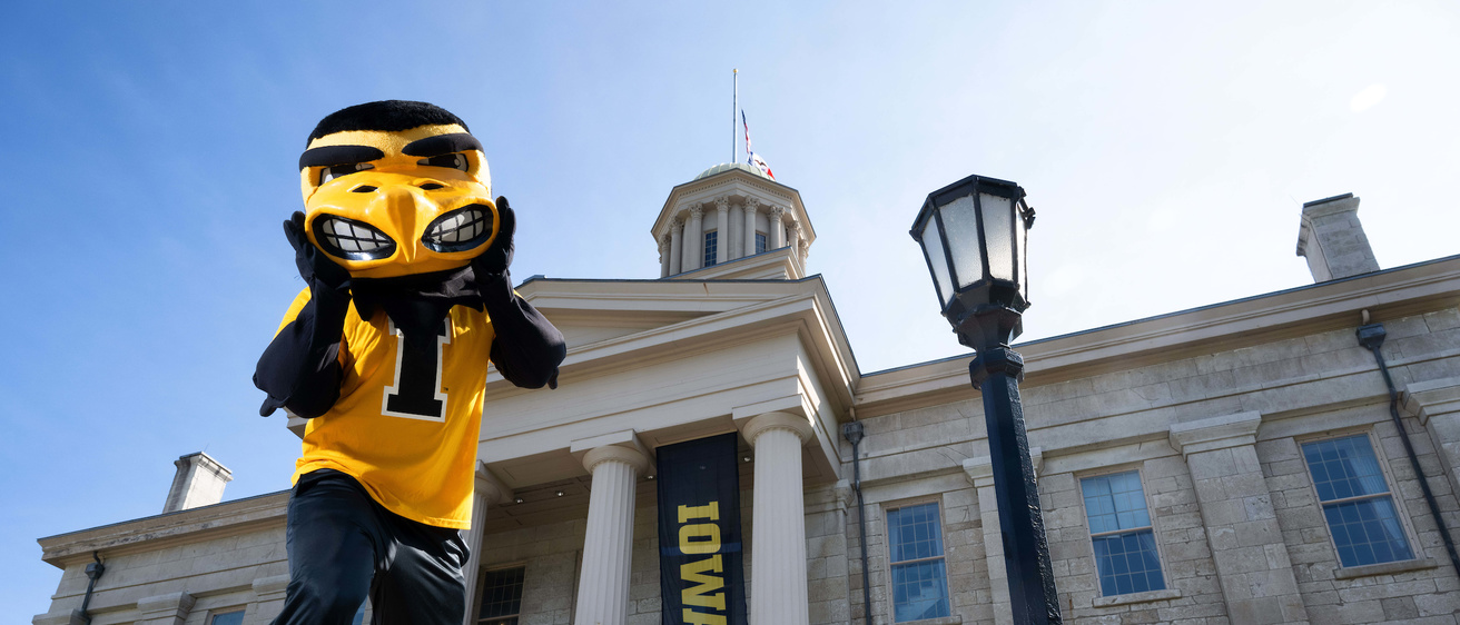 Herky, the University of Iowa mascot, standing in front of the Old Capitol building 